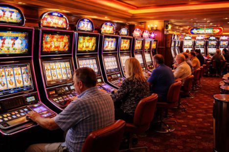 Sala de juegos en un casino español con máquinas tragamonedas y jugadores atentos a sus pantallas iluminadas.