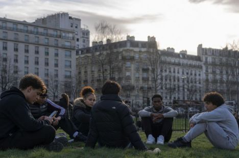 Adolescentes de diversas etnias en un parque urbano de Francia, mostrando descontento ante la puesta de sol.